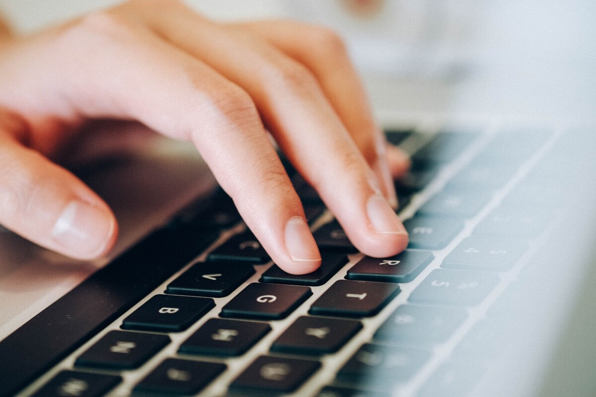 Hände, die auf eine schwarze Tastatur eines Laptops tippt. Unsere Kurse zielen darauf ab, dir das professionelle Schreiben zu zeigen.